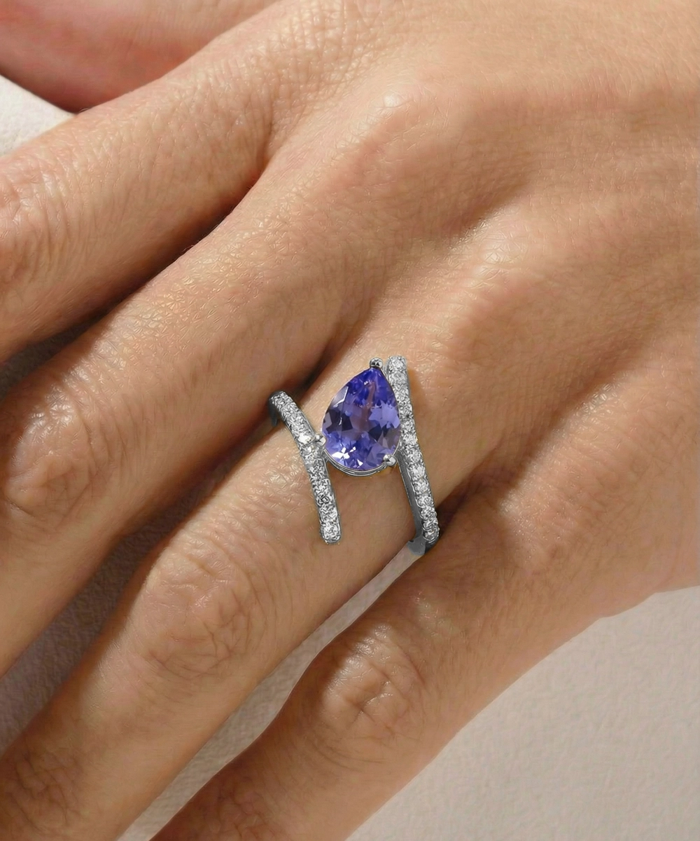 Ring with a purple gemstone on a hand against a neutral background