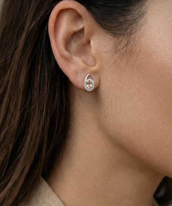 Close-up of an ear wearing a silver earring with a clear gemstone.