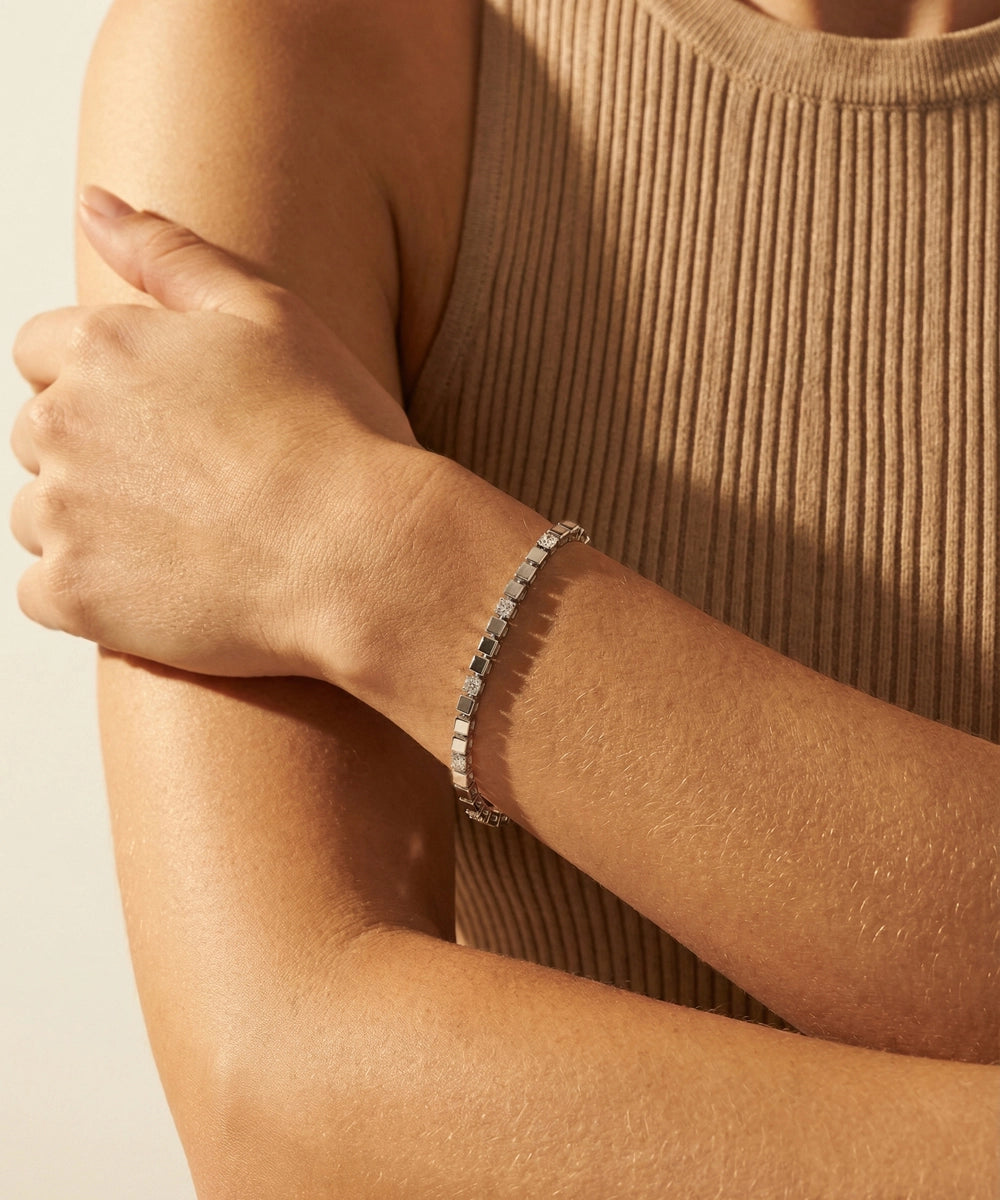 Silver bracelet on a person's wrist with a neutral background