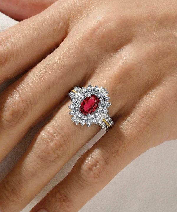 Silver ring with a red gemstone on a hand against a neutral background
