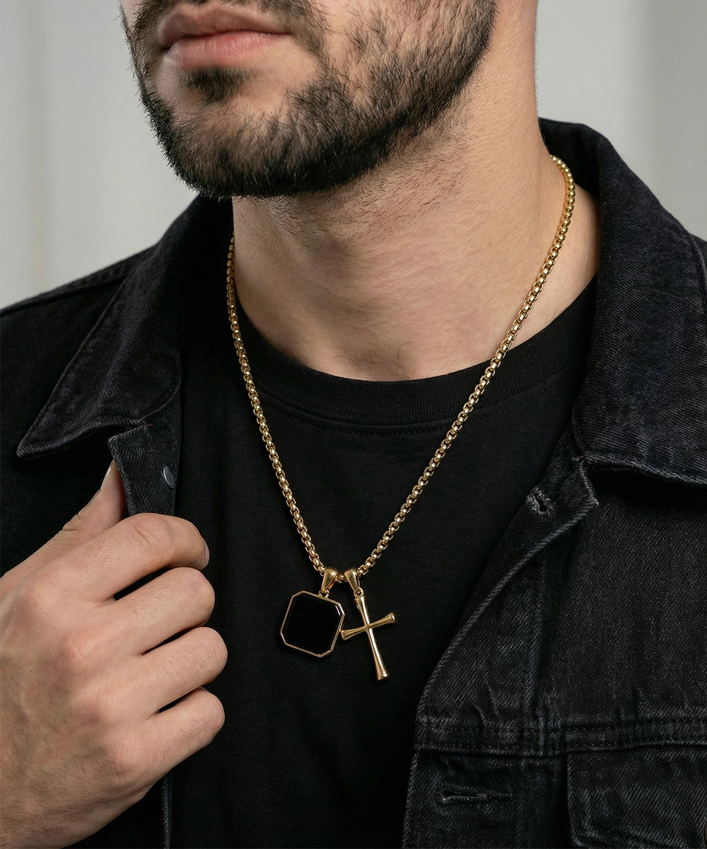 Man wearing a gold chain with a pendant, dressed in black clothing.