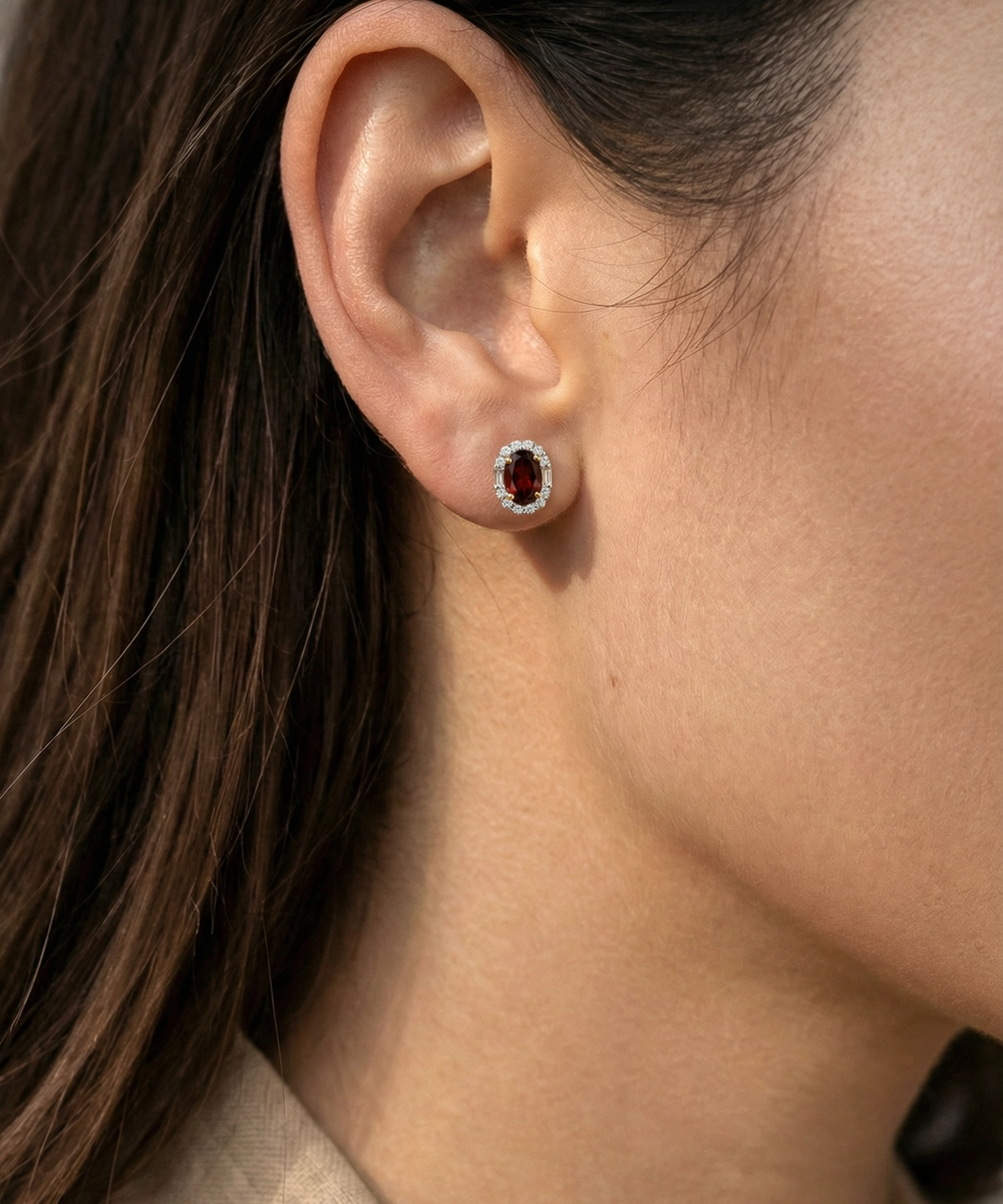 Close-up of an ear wearing a silver earring with a red gemstone.