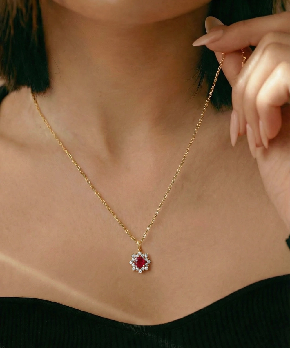 Gold necklace with a red gemstone pendant worn by a person