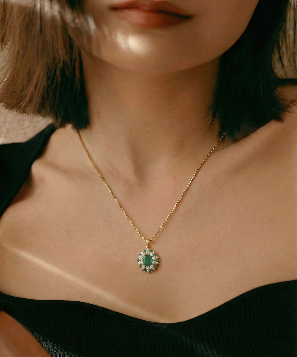 Close-up of a person wearing a gold necklace with an emerald pendant.