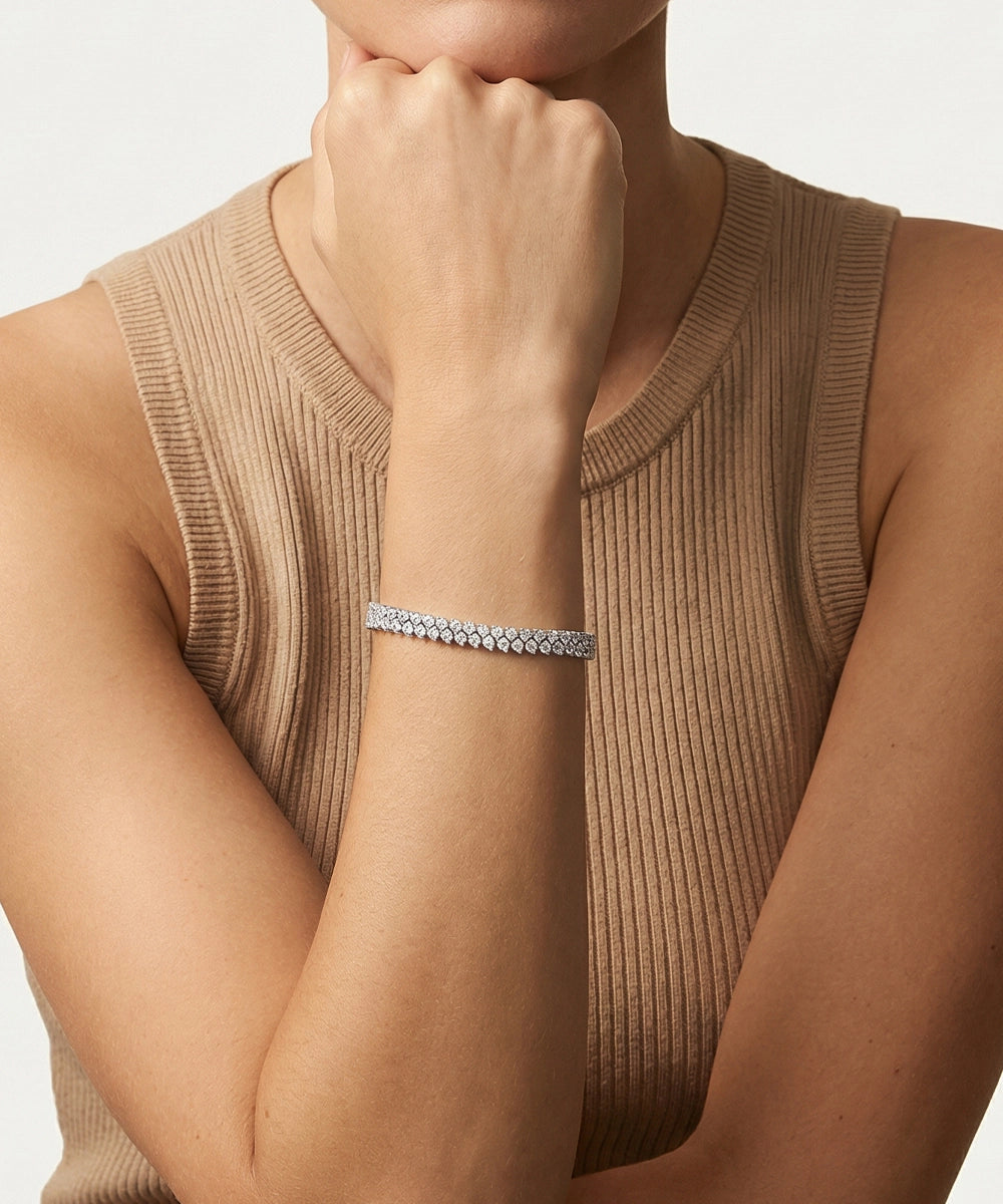 Person wearing a silver bracelet on a neutral background