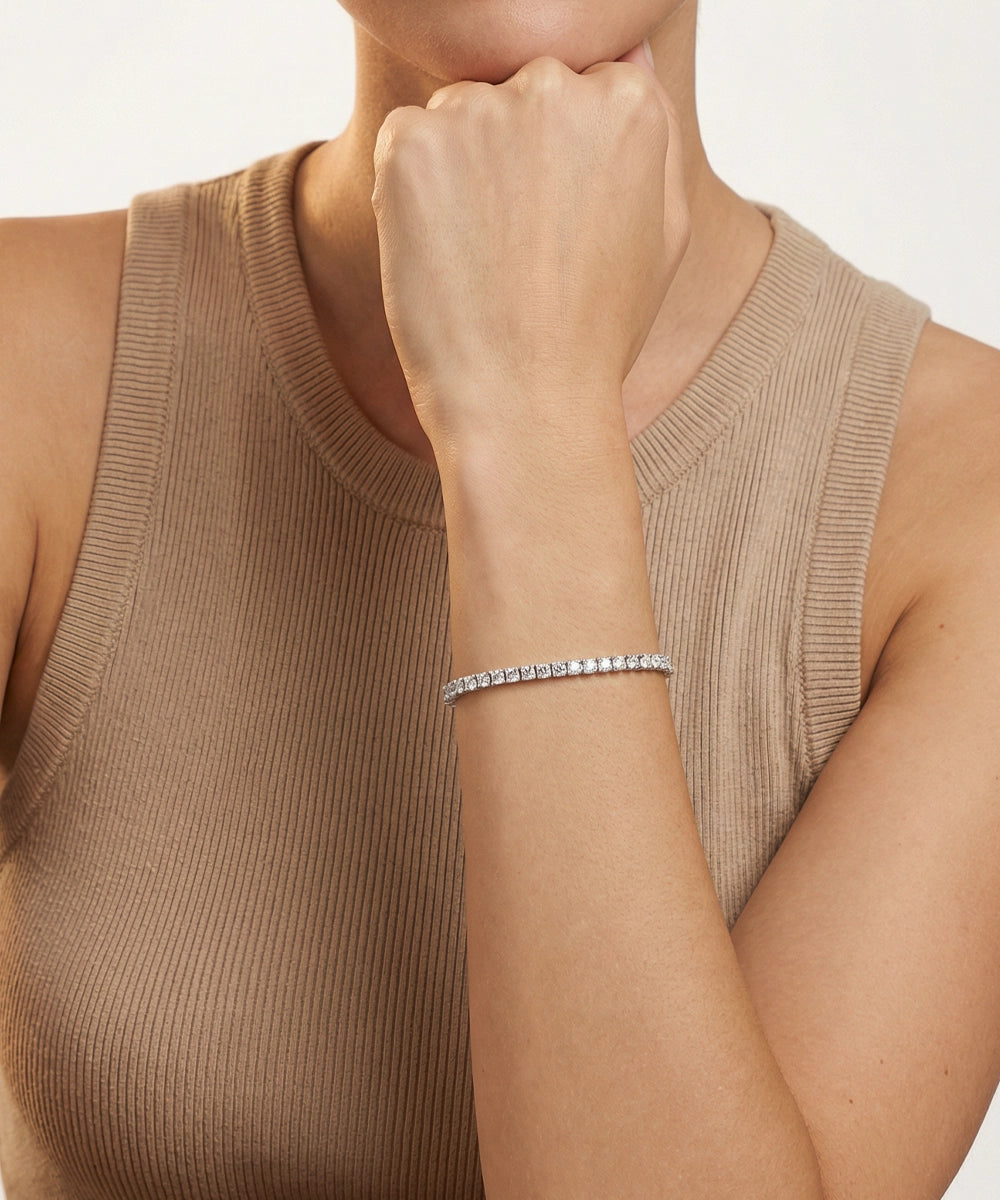 Person wearing a silver bracelet on a plain background