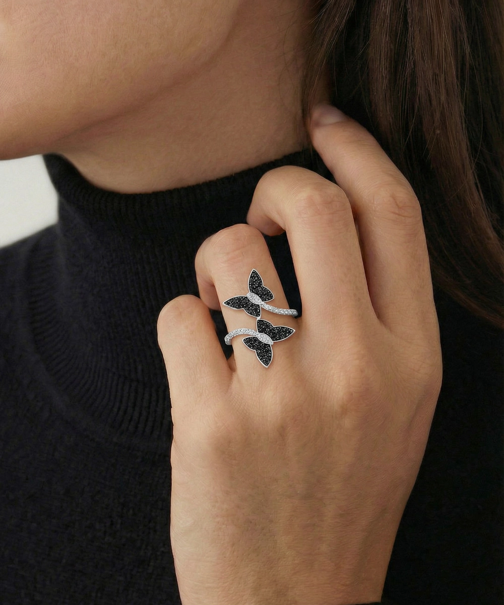 Close-up of a hand wearing a decorative ring with black and white stones against a blurred background.