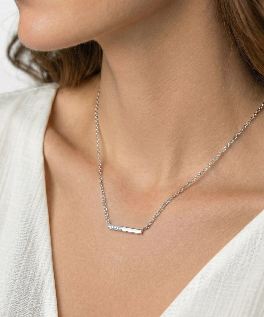 Silver necklace with a paw-shaped pendant worn by a person in a white top.