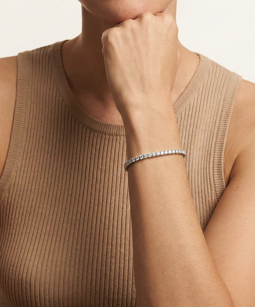 Close-up of a person wearing a silver bracelet on a neutral background