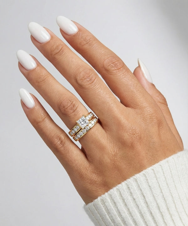 Hand wearing a gold ring with diamonds on a neutral background
