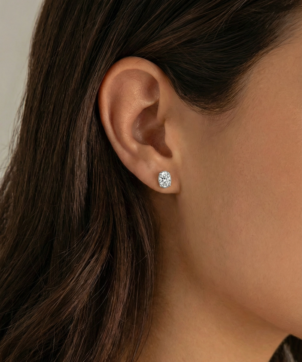 Close-up of an ear wearing a diamond stud earring with a neutral background