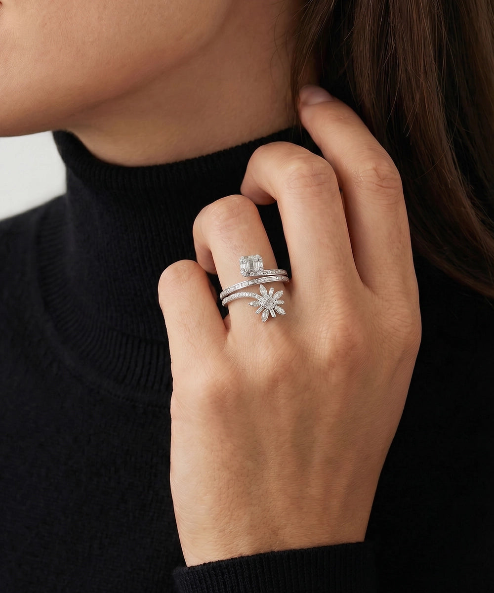 Close-up of a hand wearing multiple silver rings with a black background