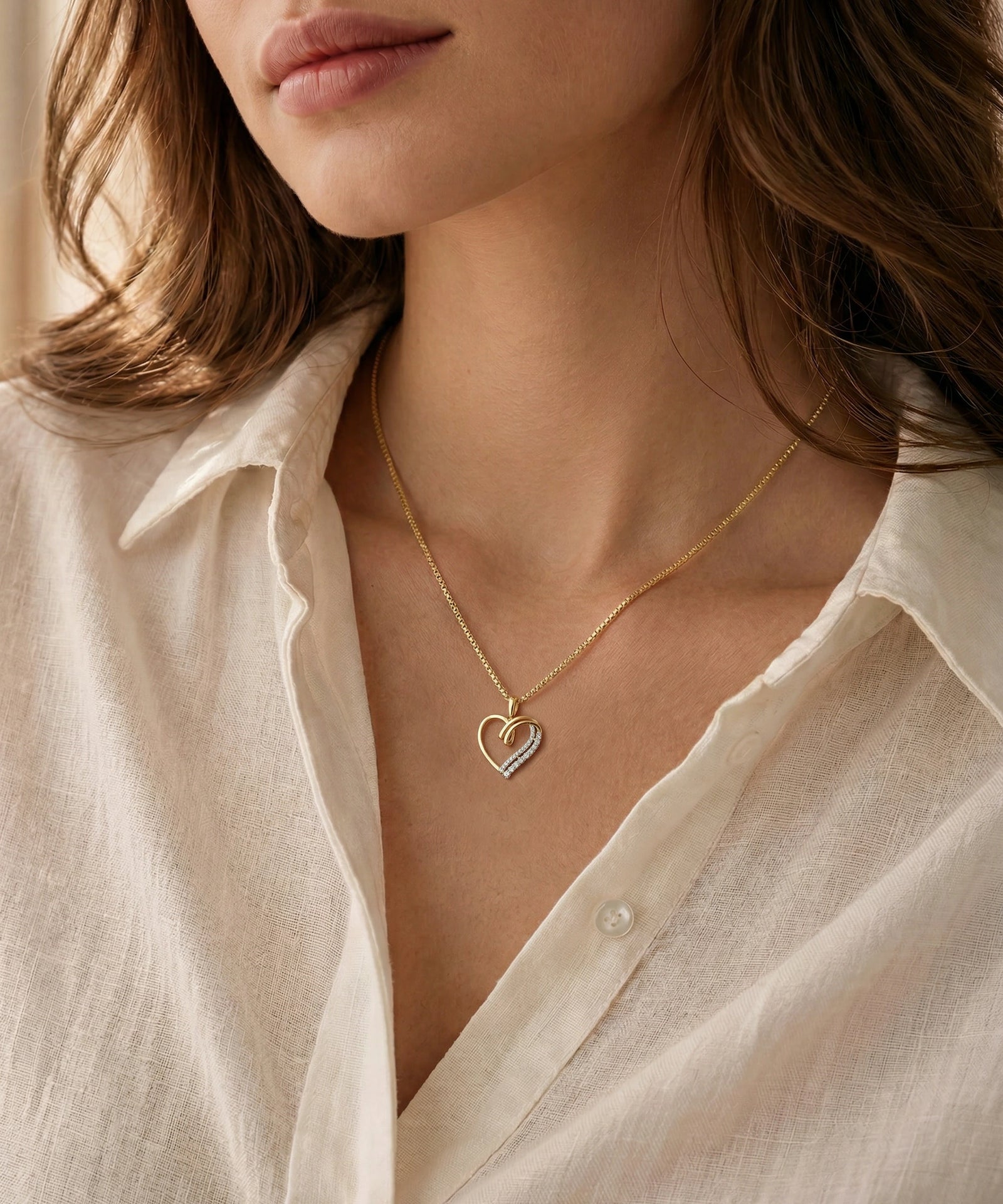 Woman wearing a gold necklace with a heart pendant against a neutral background