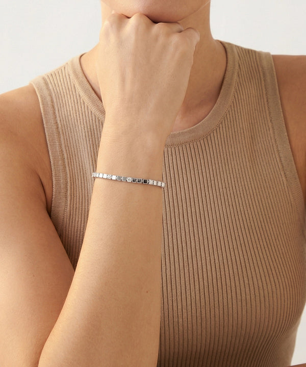 Person wearing a silver bracelet on a plain background