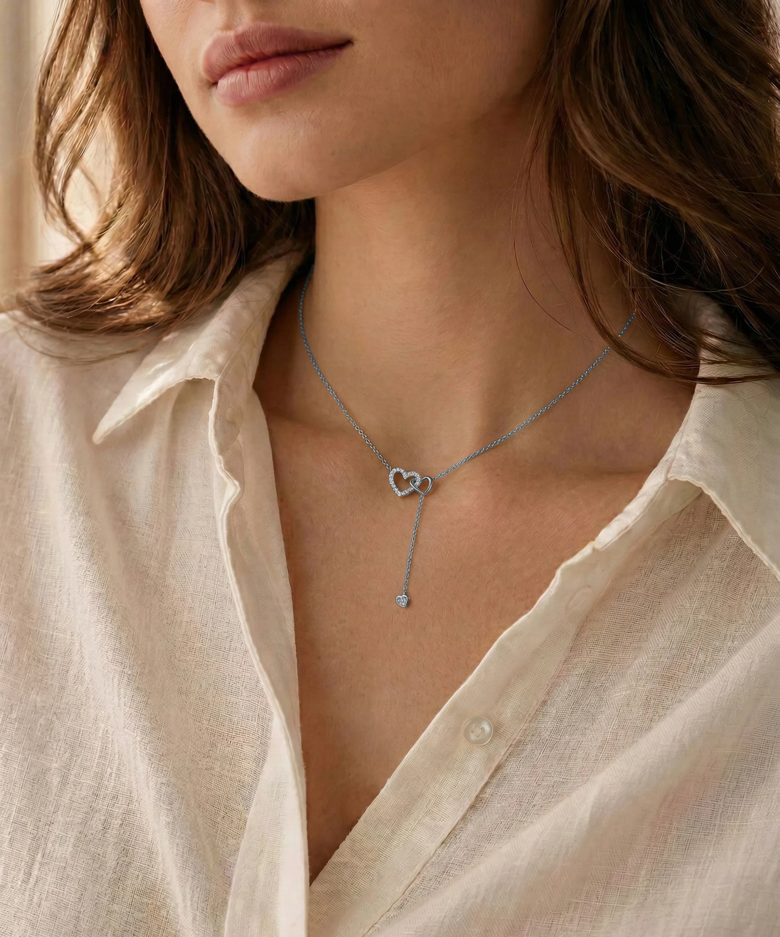 Close-up of a person wearing a delicate gold necklace with a heart pendant.