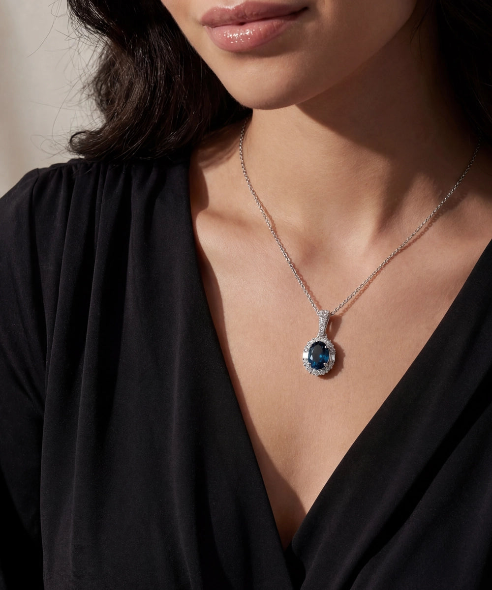 Close-up of a woman wearing a necklace with a blue gemstone pendant.