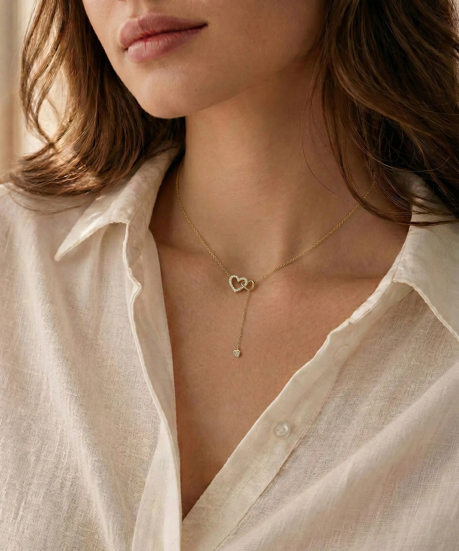 Close-up of a person wearing a delicate gold necklace with a heart pendant.