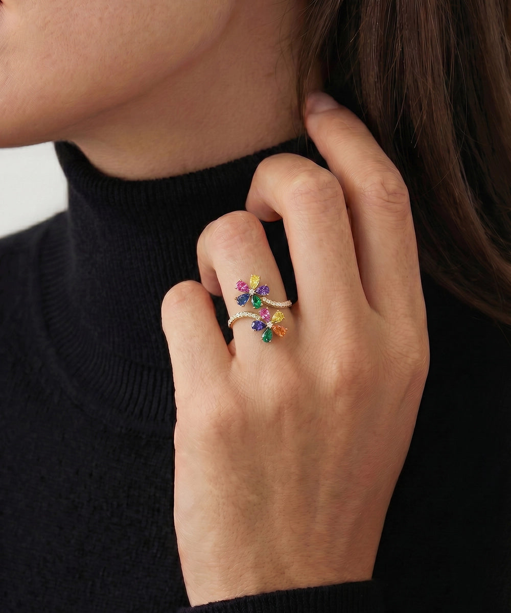 Close-up of a hand wearing a colorful floral ring against a black background