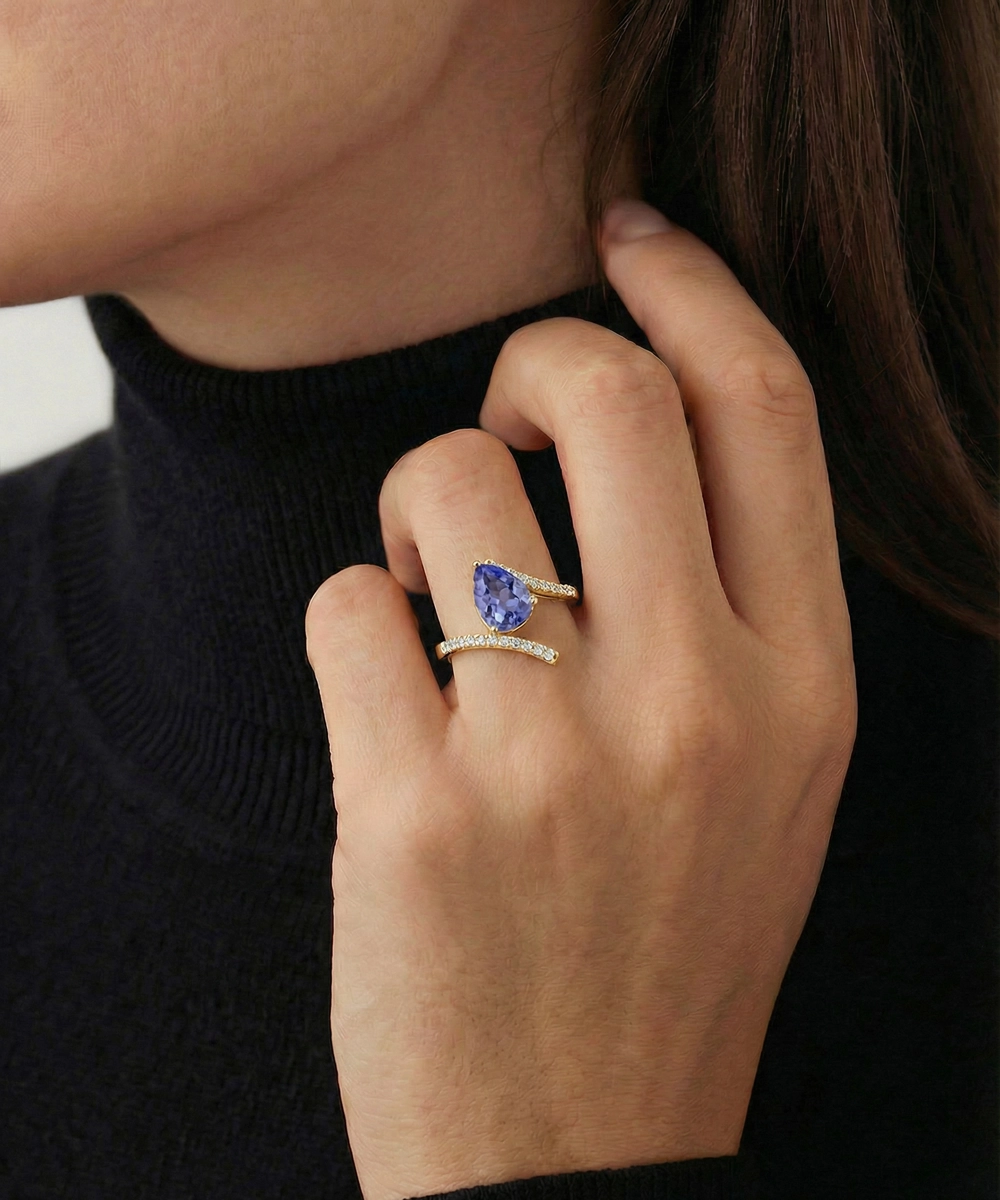 Close-up of a hand wearing two rings with gemstones against a dark background