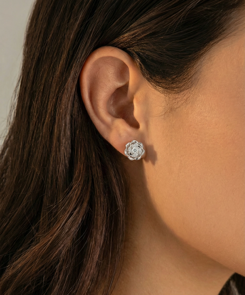 Close-up of an ear wearing a silver floral earring with a blurred background