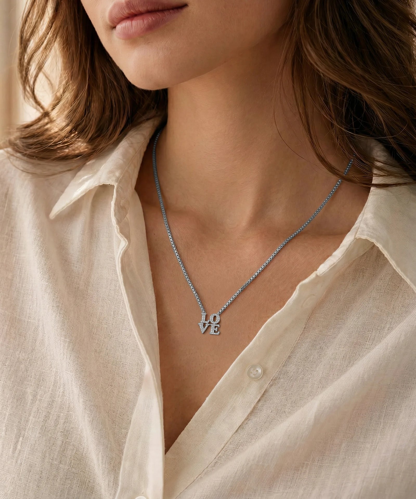 Necklace with a circular pendant worn by a person in a light-colored shirt.