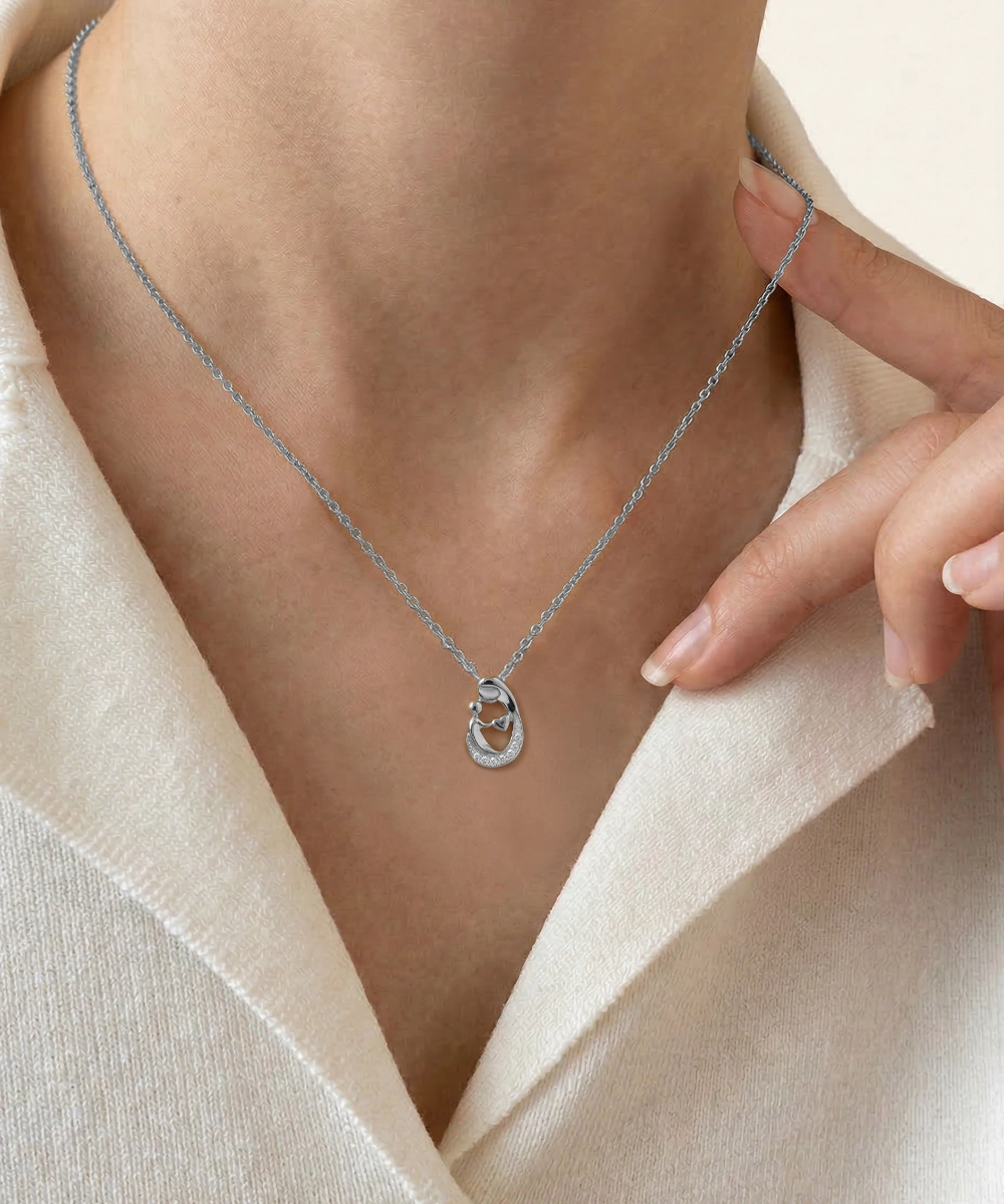 Silver necklace with a pendant worn by a person against a neutral background