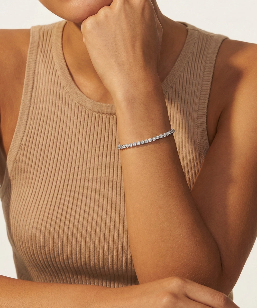Woman wearing a beige ribbed tank top and diamond bracelet on a neutral background