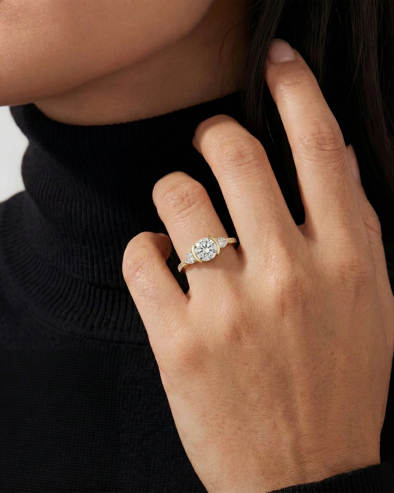 Close-up of a hand wearing a gold ring with a diamond on a plain background
