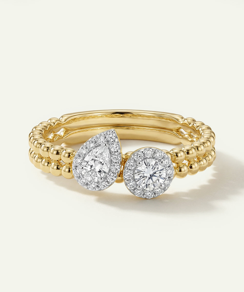 Gold ring with two diamond stones on a light gray background