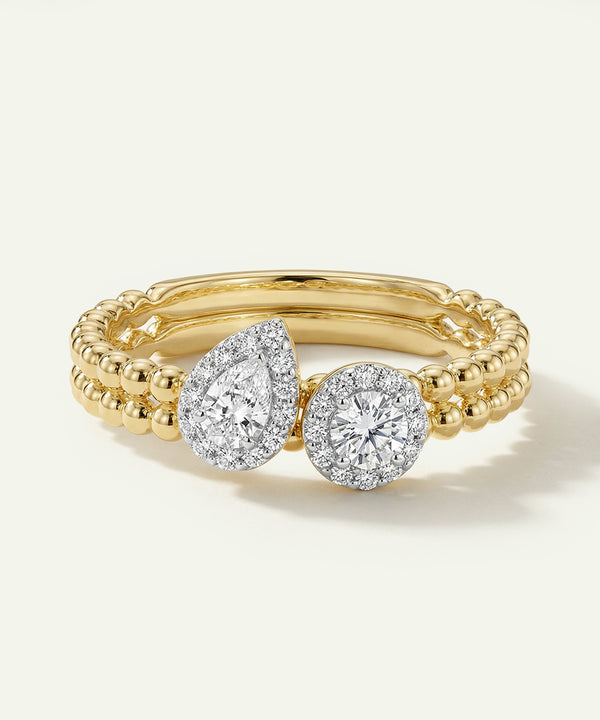Gold ring with two diamond stones on a light gray background