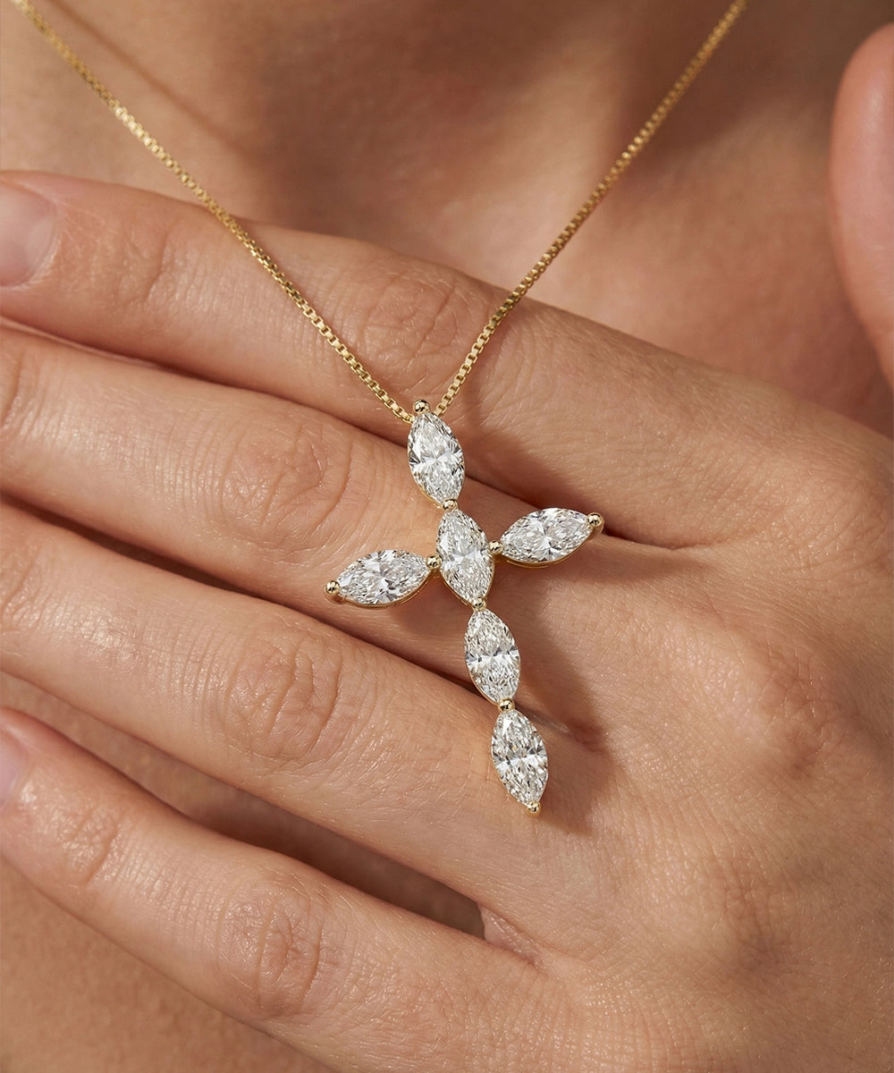 Gold necklace with a diamond pendant held by a hand