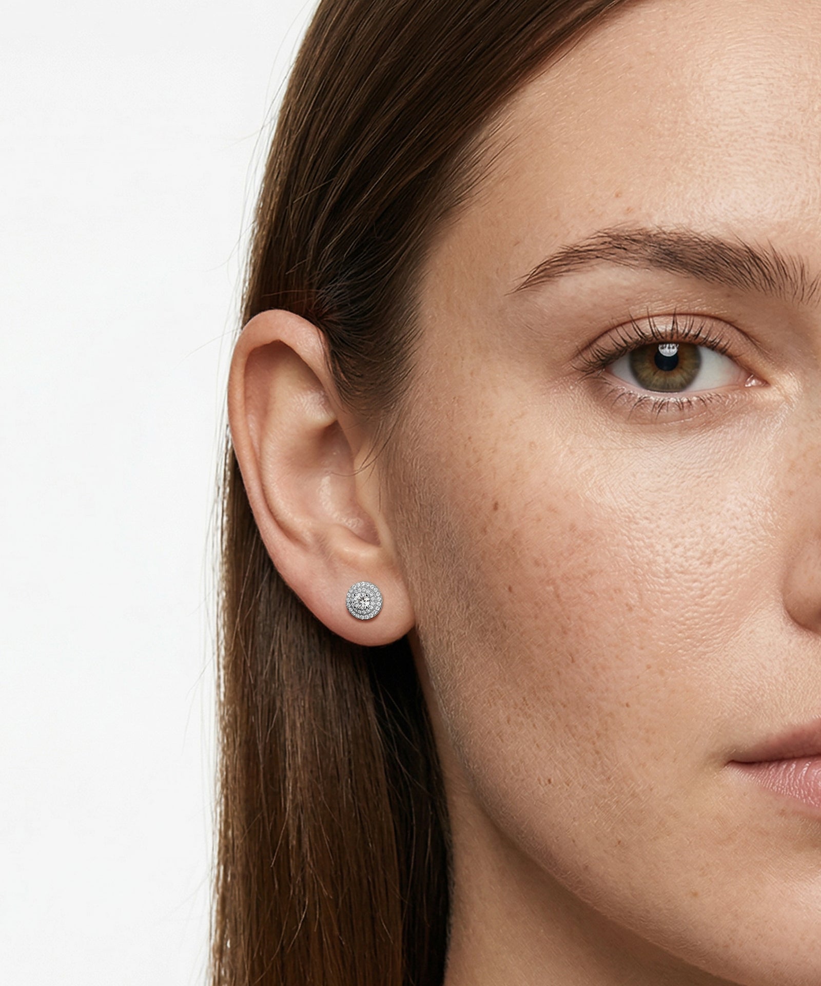 Close-up of a woman wearing a diamond stud earring on a white background