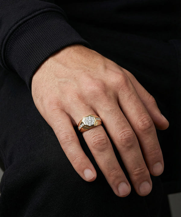 Hand wearing a gold ring with a diamond on a black background