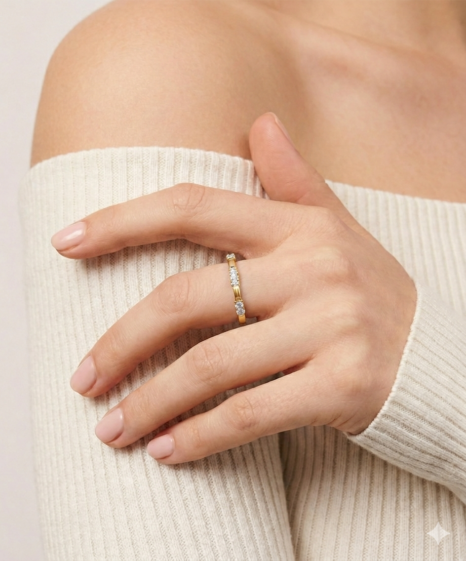 Hand wearing a gold ring with a beige sweater background