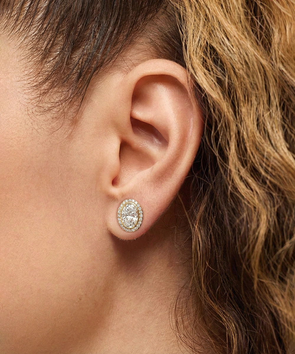 Close-up of an ear wearing a diamond earring with hair partially covering the frame.
