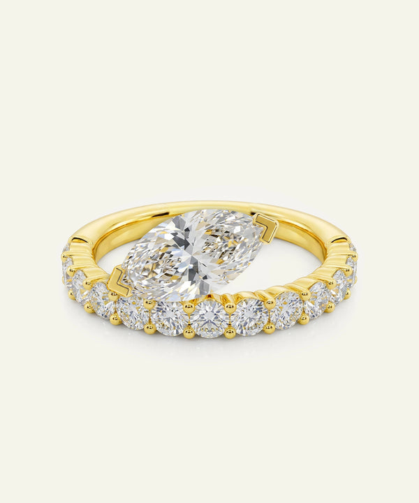 Gold ring with a large diamond and smaller diamonds on a light beige background