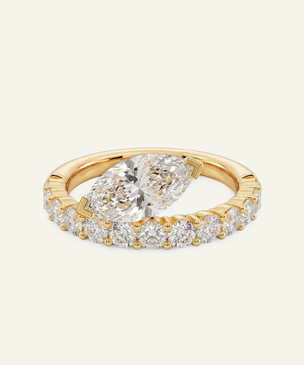 Gold ring with a large diamond and smaller diamonds on a light beige background