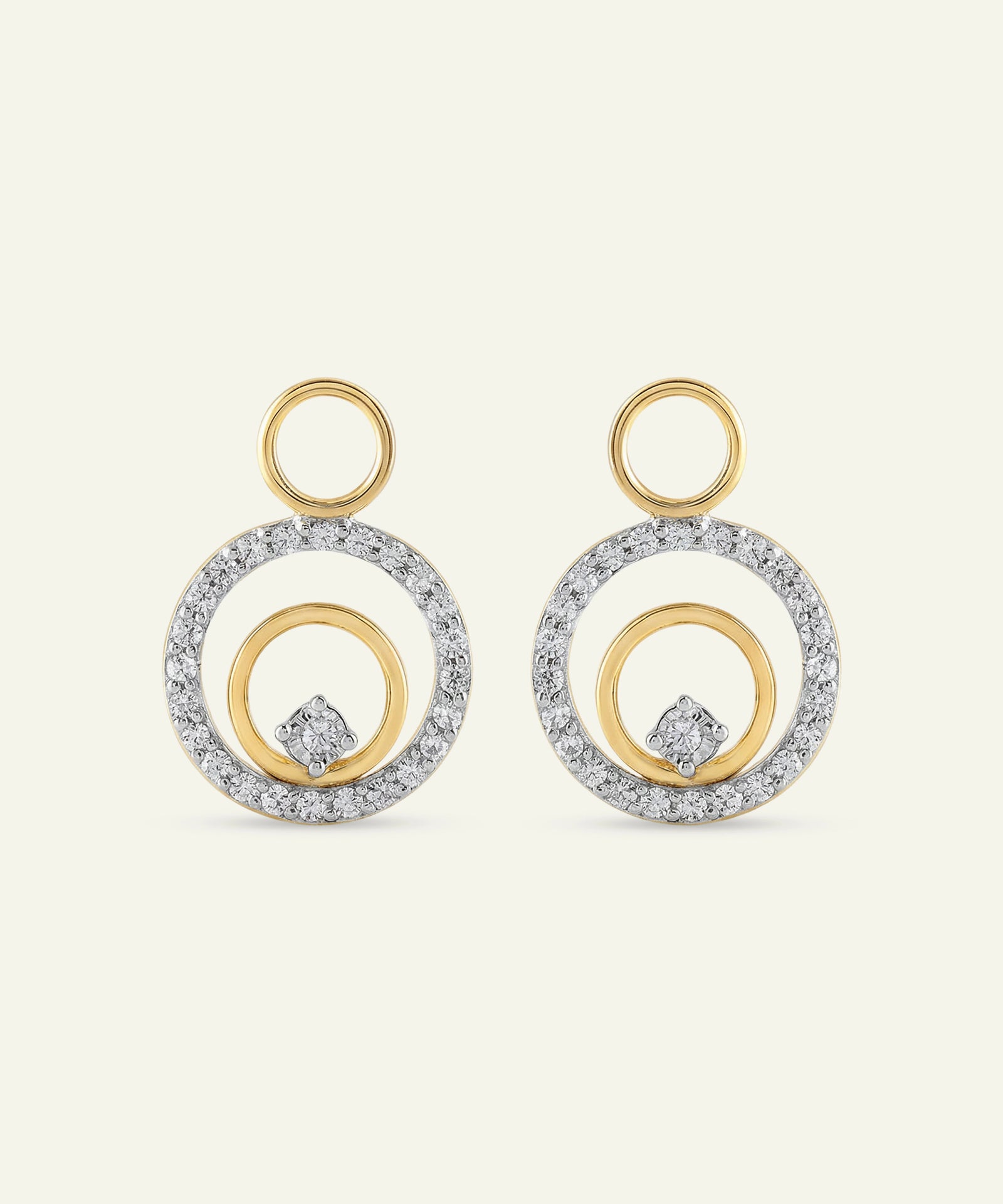 Pair of gold and silver hoop earrings on a light beige background