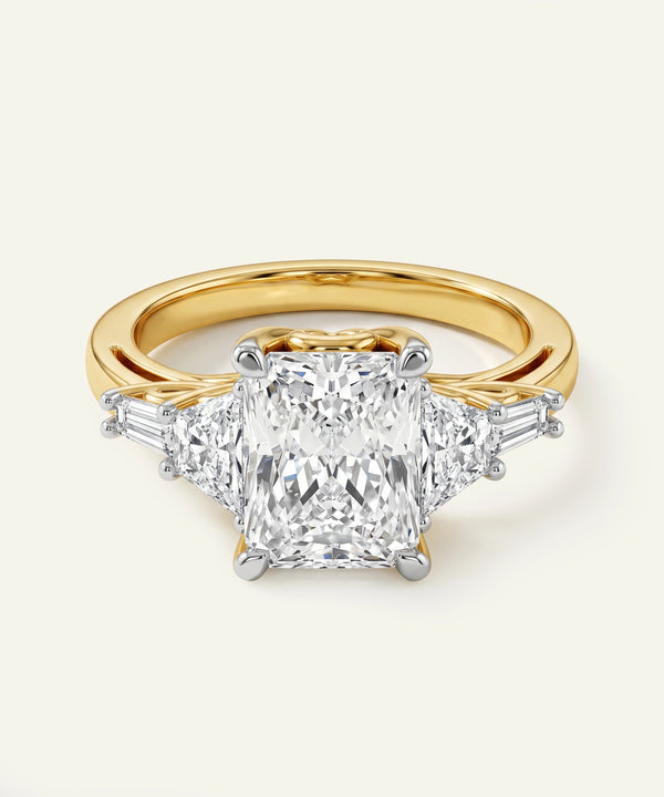 Gold ring with a large diamond and smaller diamonds on the band against a light background
