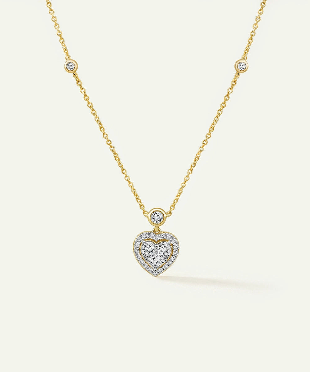 Gold necklace with a heart-shaped diamond pendant on a white background
