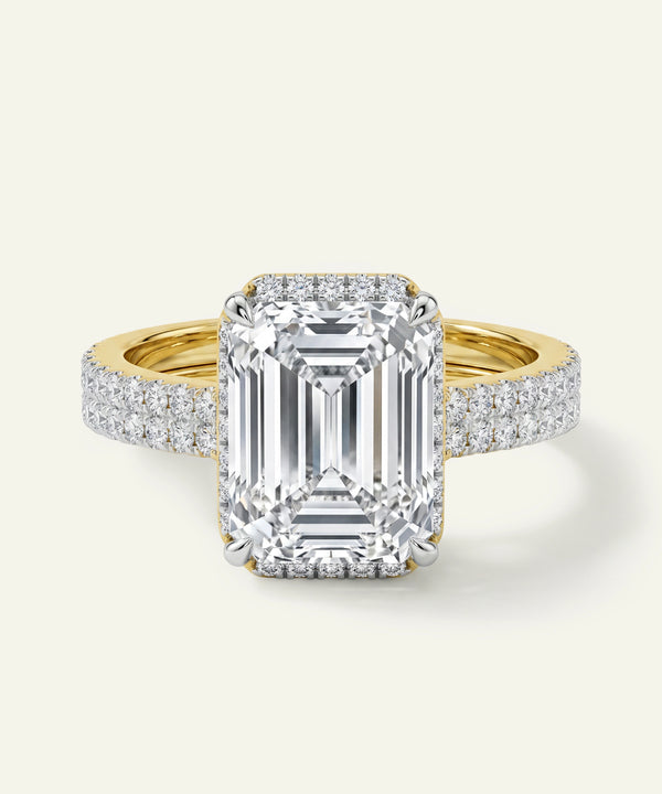 Gold ring with a large diamond and smaller diamonds on the band against a white background