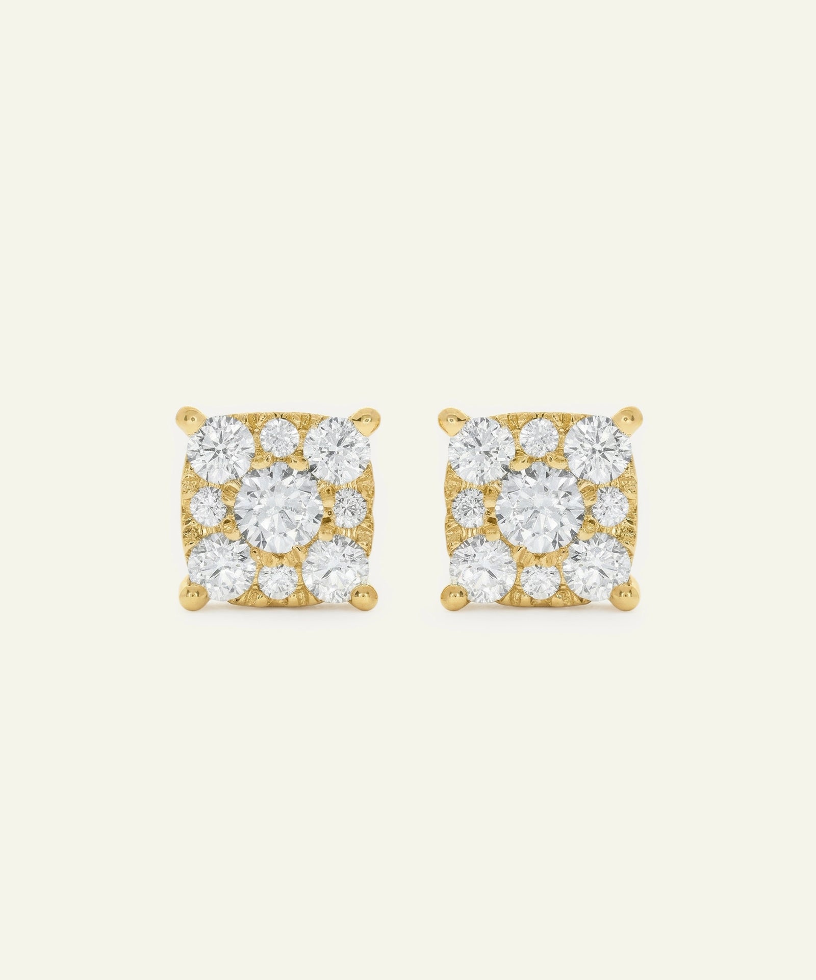 Pair of gold square-shaped earrings with clear gemstones on a light beige background