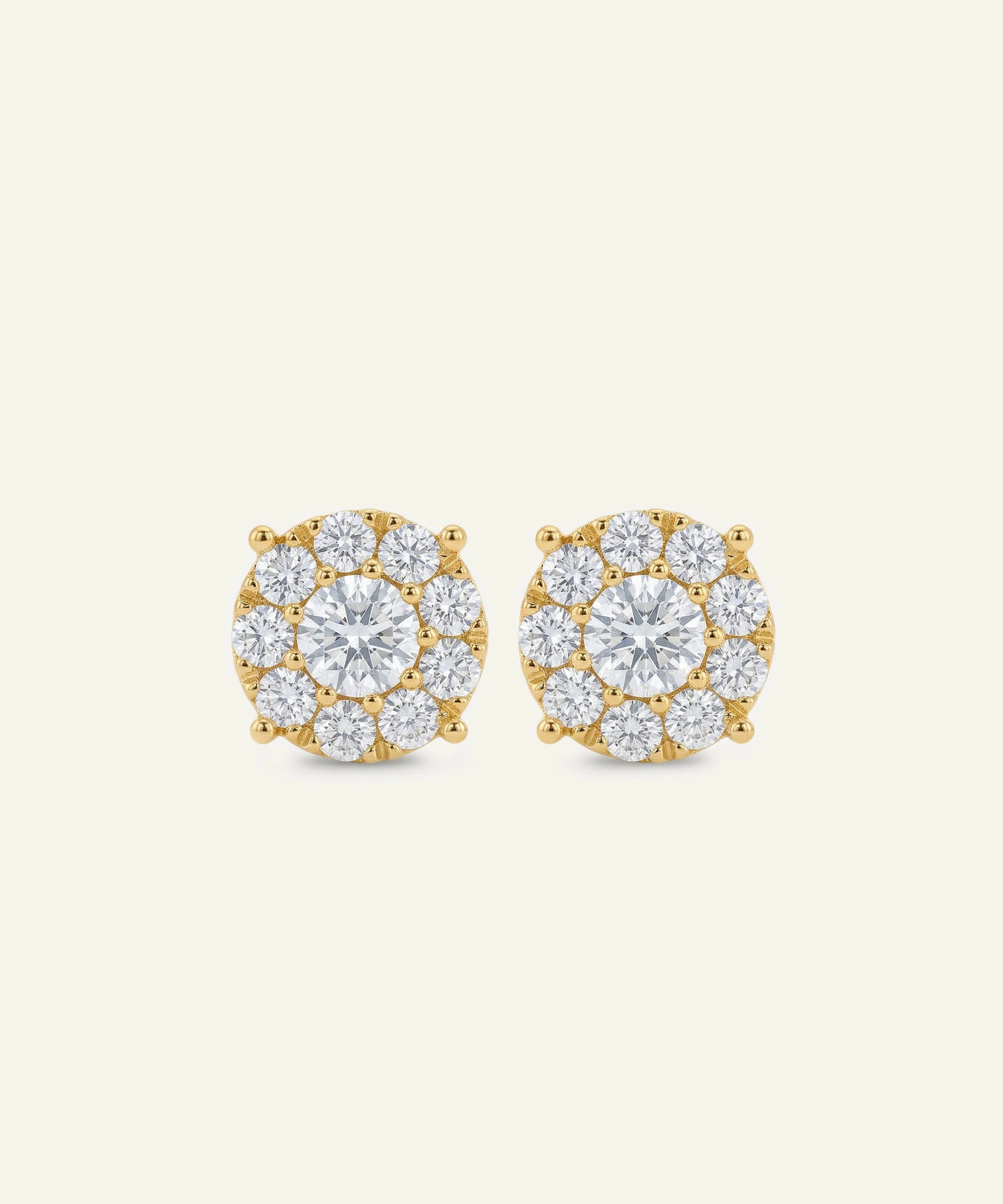 Pair of gold and diamond earrings on a light beige background