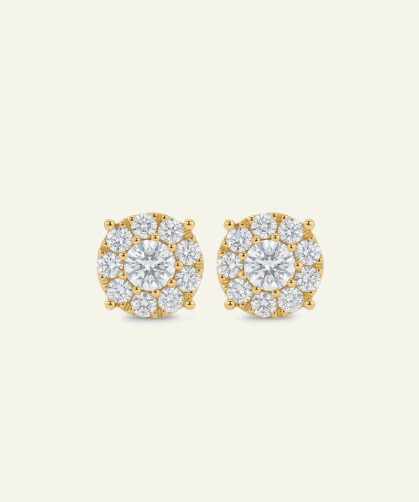 Pair of gold and diamond earrings on a light beige background