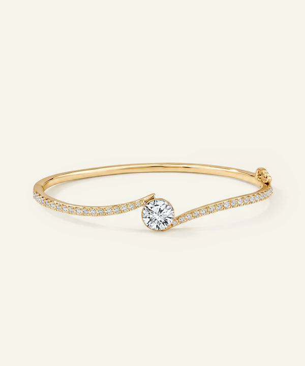 Gold bracelet with a diamond on a light beige background