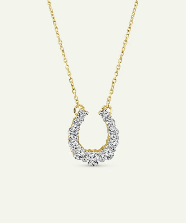 Gold necklace with a horseshoe-shaped pendant on a white background
