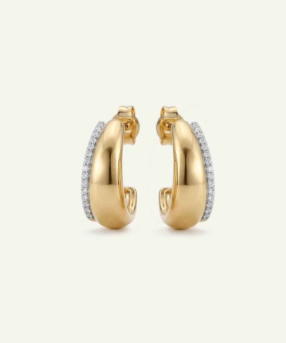 Gold hoop earrings with embedded diamonds on a light beige background