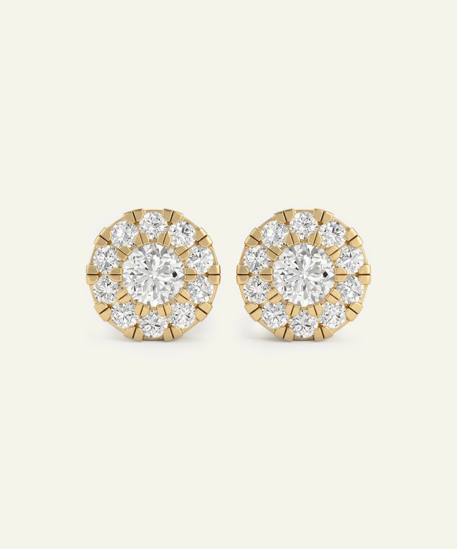 Pair of gold and diamond stud earrings on a light beige background