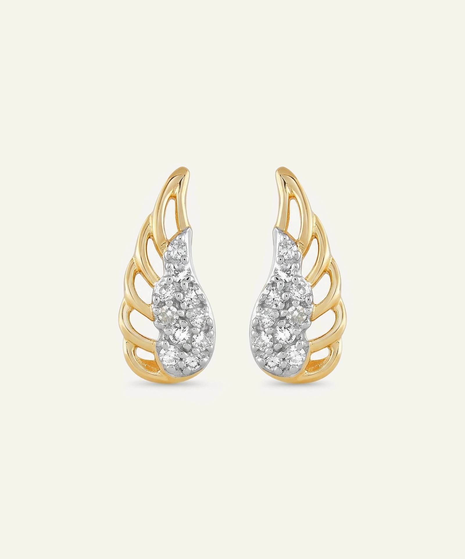 Gold and silver wing-shaped earrings on a light beige background