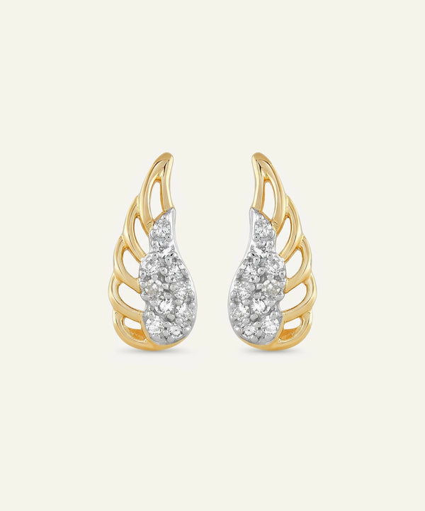 Gold and silver wing-shaped earrings on a light beige background